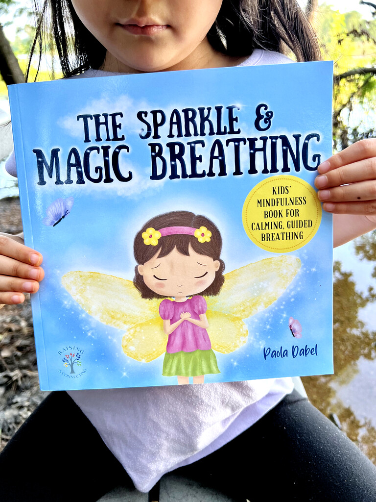 Child holding The Sparkle and Magic Breathing book
